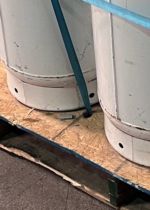 The vertical strap passing through the pallet deck between two cylinders